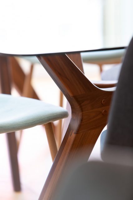 Détail sur la table en verre et piétement en noyer AMPM et les chaises tissées vert de gris de la salle à manger du projet Paris 16.